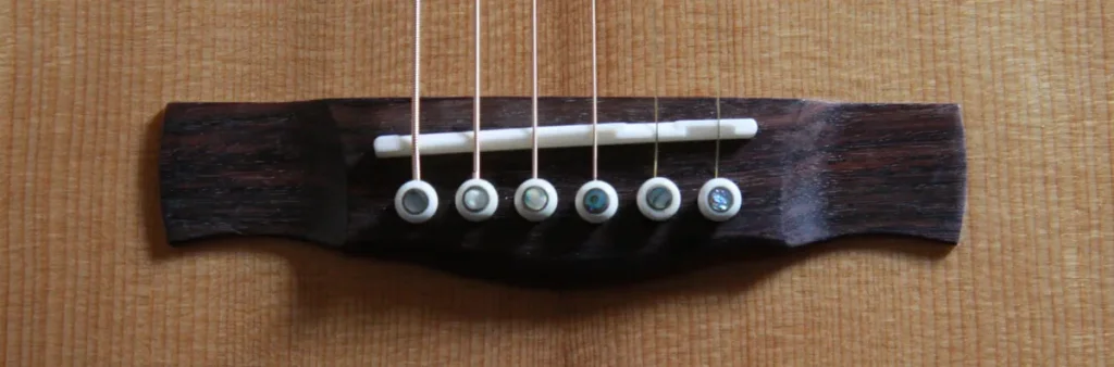 Dettaglio del ponte in Ebano con piroli decorati in madreperla su top in Abete - Corsalini Guitars.